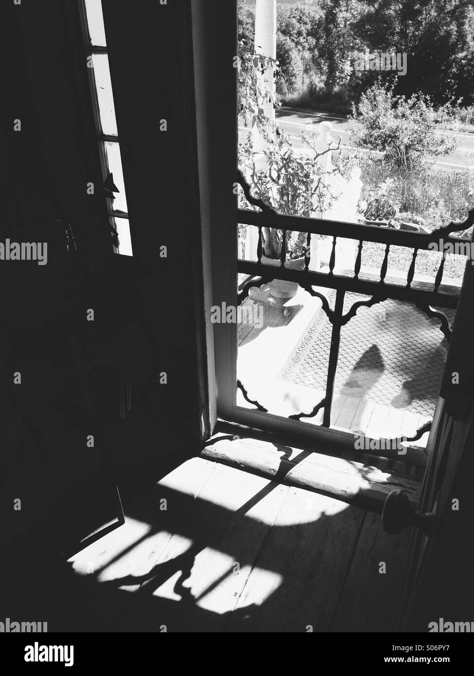 Black and white interior of an American farmhouse doorway, with sunlight shining through a screen door, USA. - Smartphone Captured Stock Image