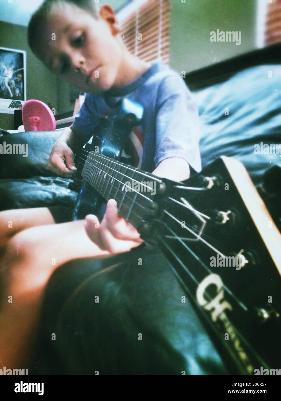 A young boy practices playing guitar Stock Photo