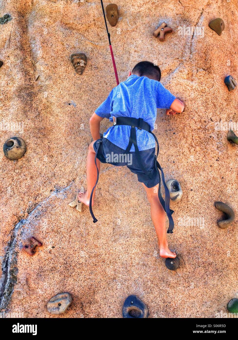 A young boy climbing a rock wall Stock Photo