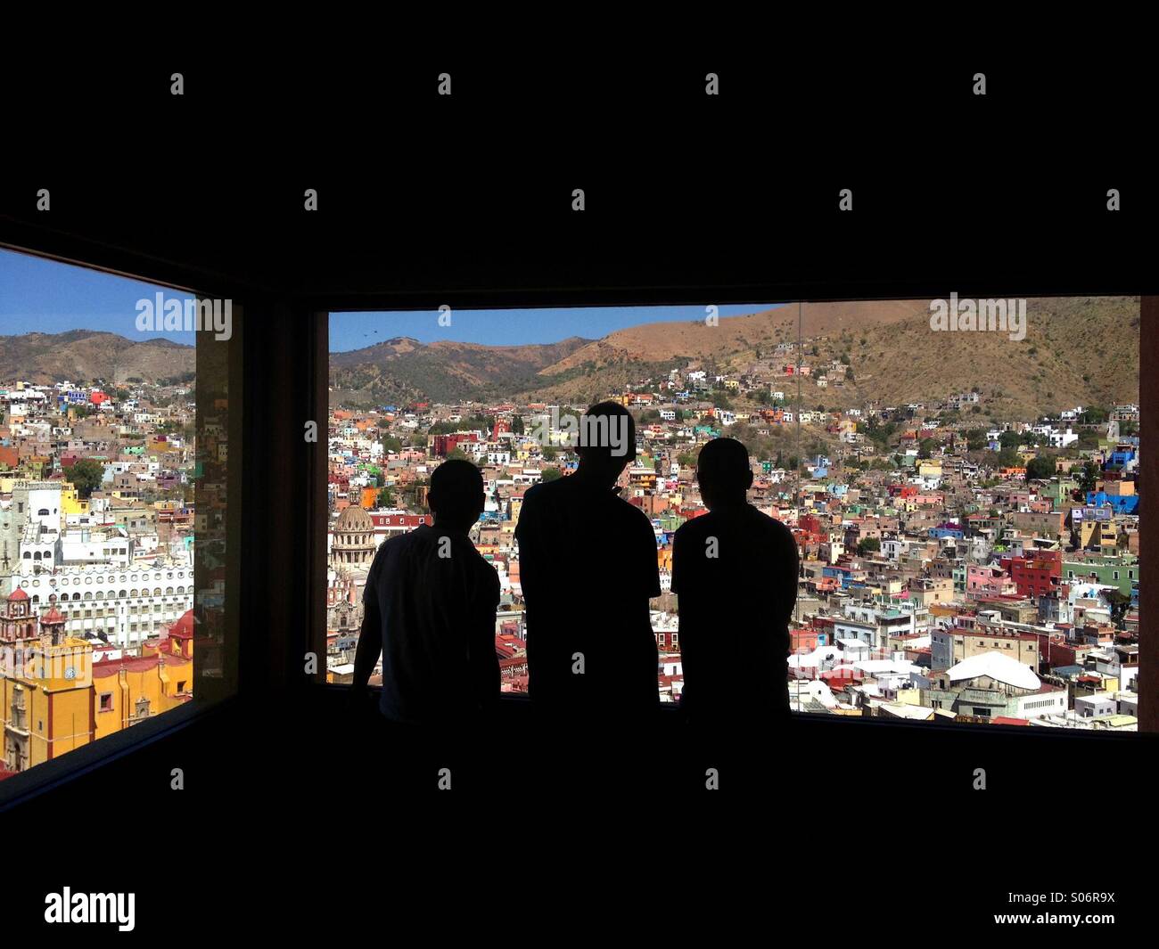 Three people looking over Guanajuato Mexico from a funicular window - Smartphone Captured Stock Image