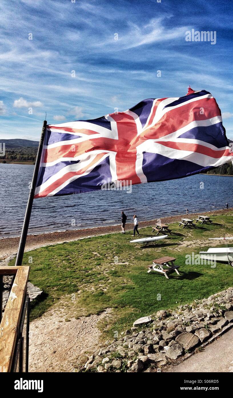 Union Flag Jack of Great Britain and Northern Ireland flying; shot against a Scottish loch lake. Vertical format - Smartphone Captured Stock Image