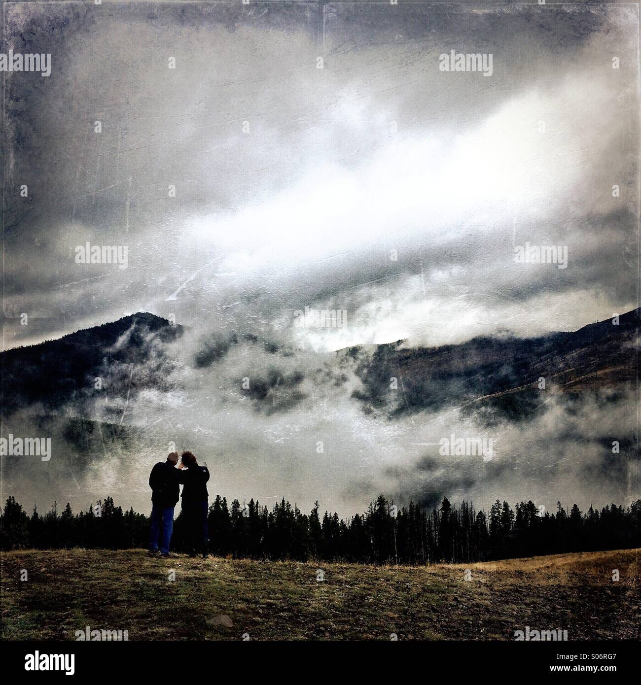 Two people stand at viewpoint in cloud bank on Dunraven Pass, Yellowstone National Park, Wyoming, USA - Smartphone Captured Stock Image