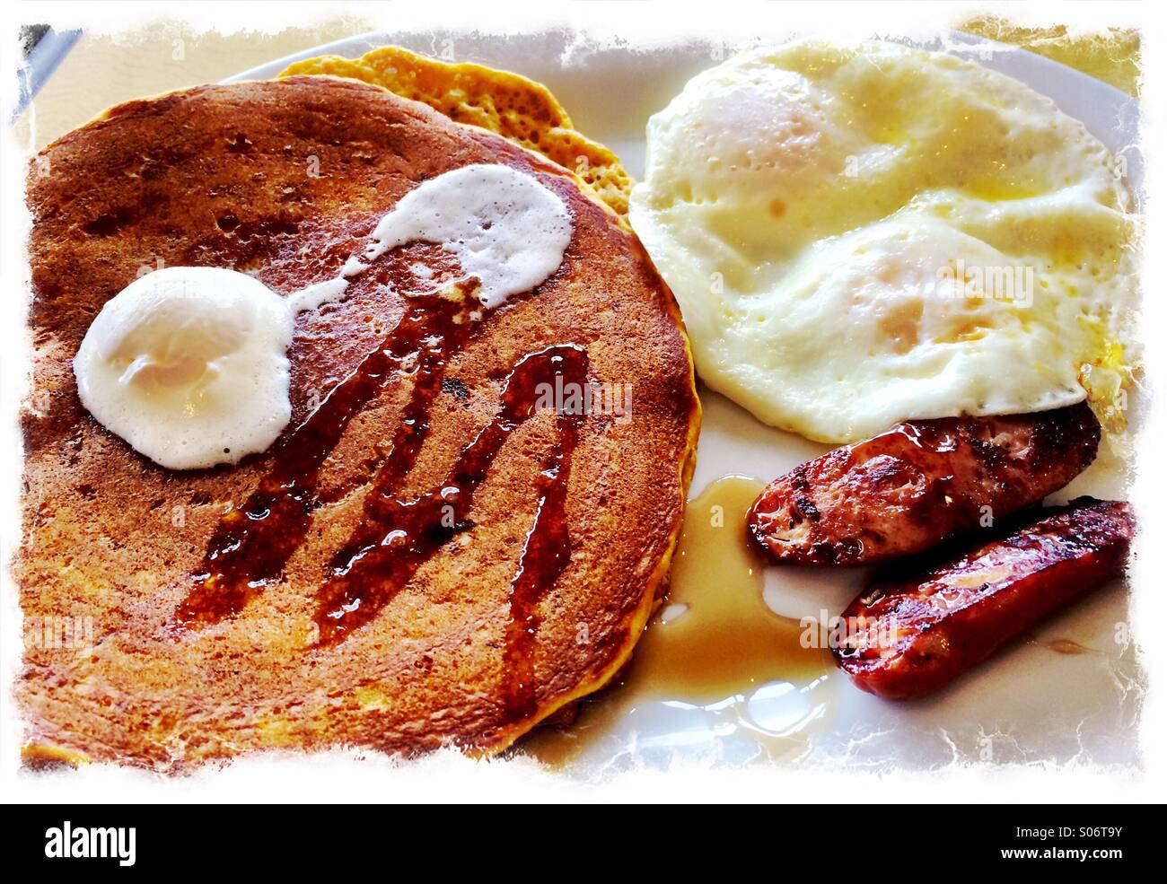 Breakfast of pancakes, syrup, eggs and sausage. Stock Photo