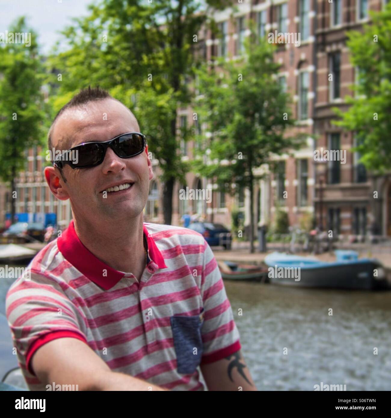 Man sitting by canal in Amsterdam - Smartphone Captured Stock Image