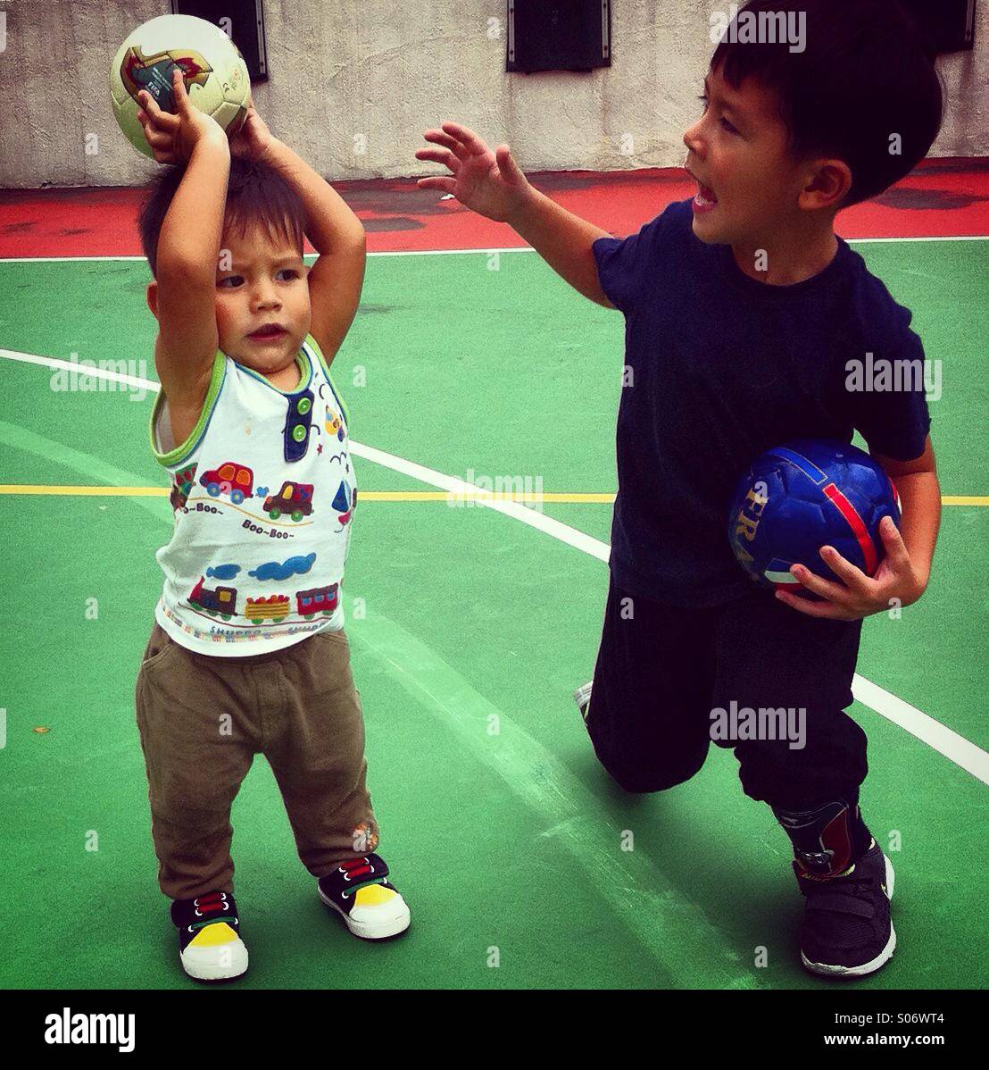 Two eurasian brothers are pkaying basketball outdoor - Smartphone Captured Stock Image