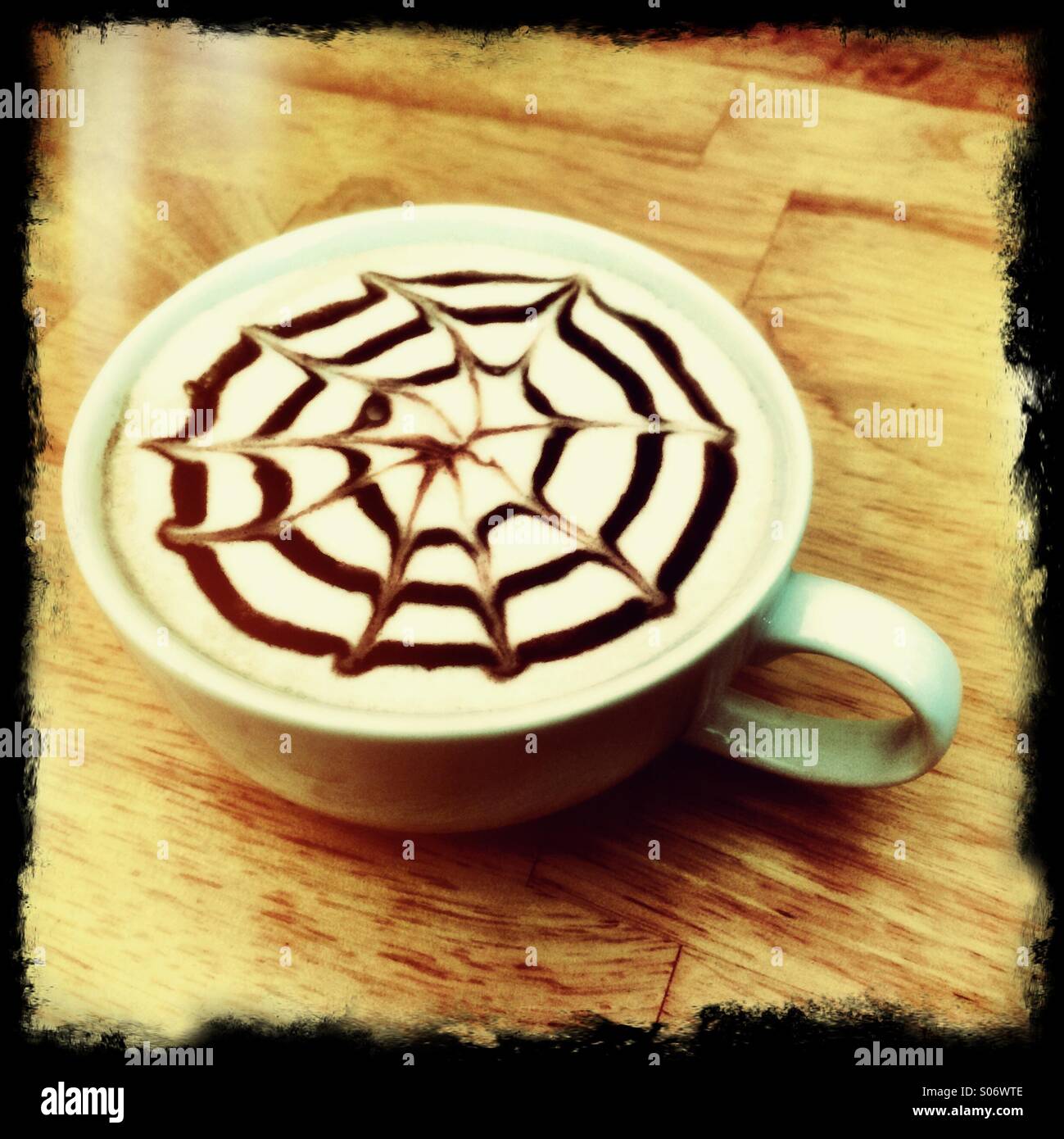 Latte coffee with a design in chocolate syrup on top. - Smartphone Captured Stock Image