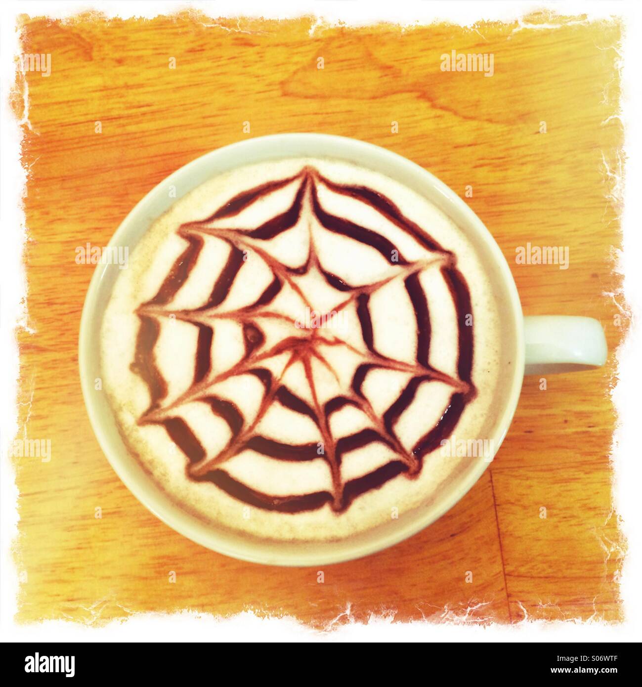 Latte coffee with a design in chocolate syrup on top. - Smartphone Captured Stock Image