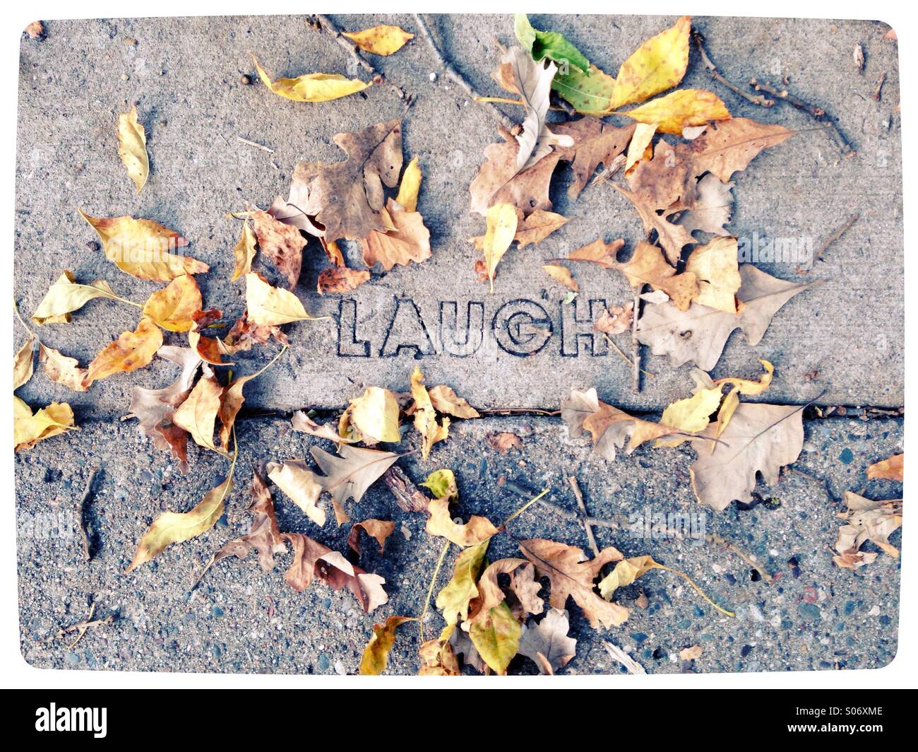 The word 'laugh' carved into a sidewalk. Stock Photo