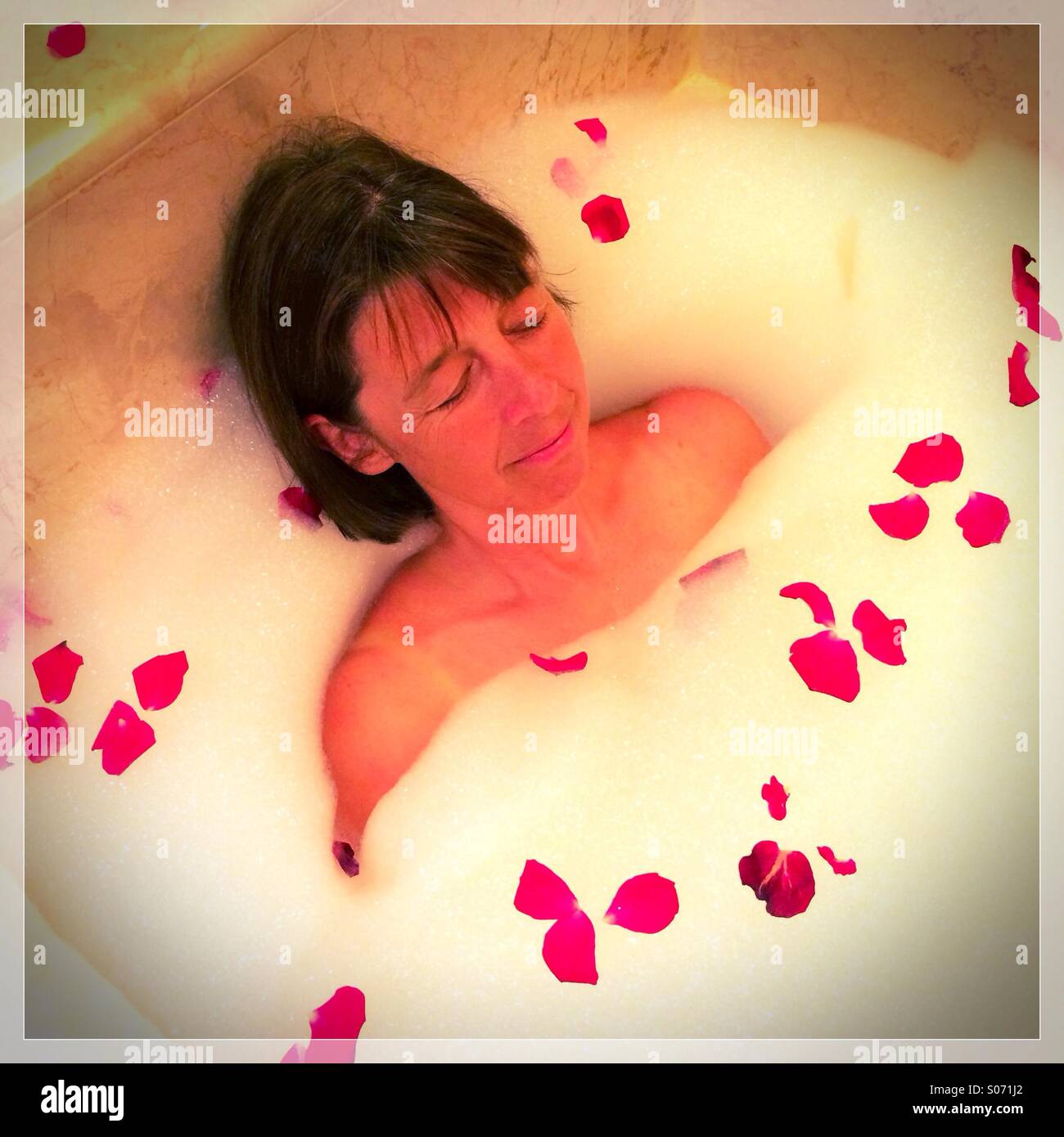 Attractive lady lying in bath with rose petals Stock Photo by NomadSoul1