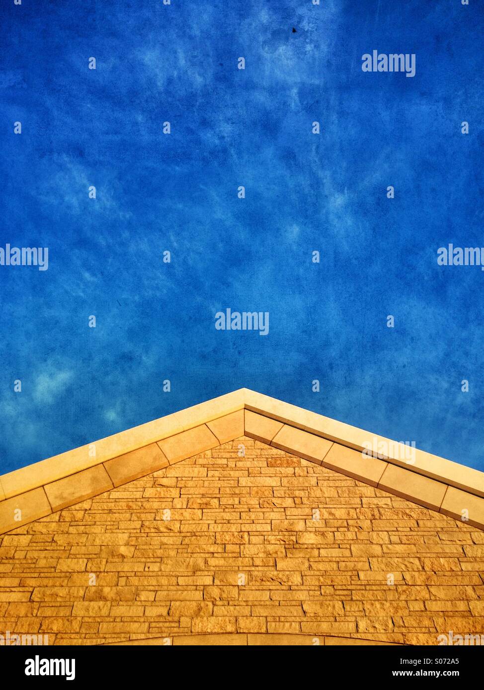 The stone front of a church reaches up into a blue sky - Smartphone Captured Stock Image