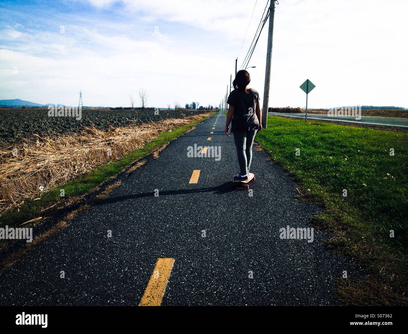 A woman skateboarding in rural Canada Stock Photo