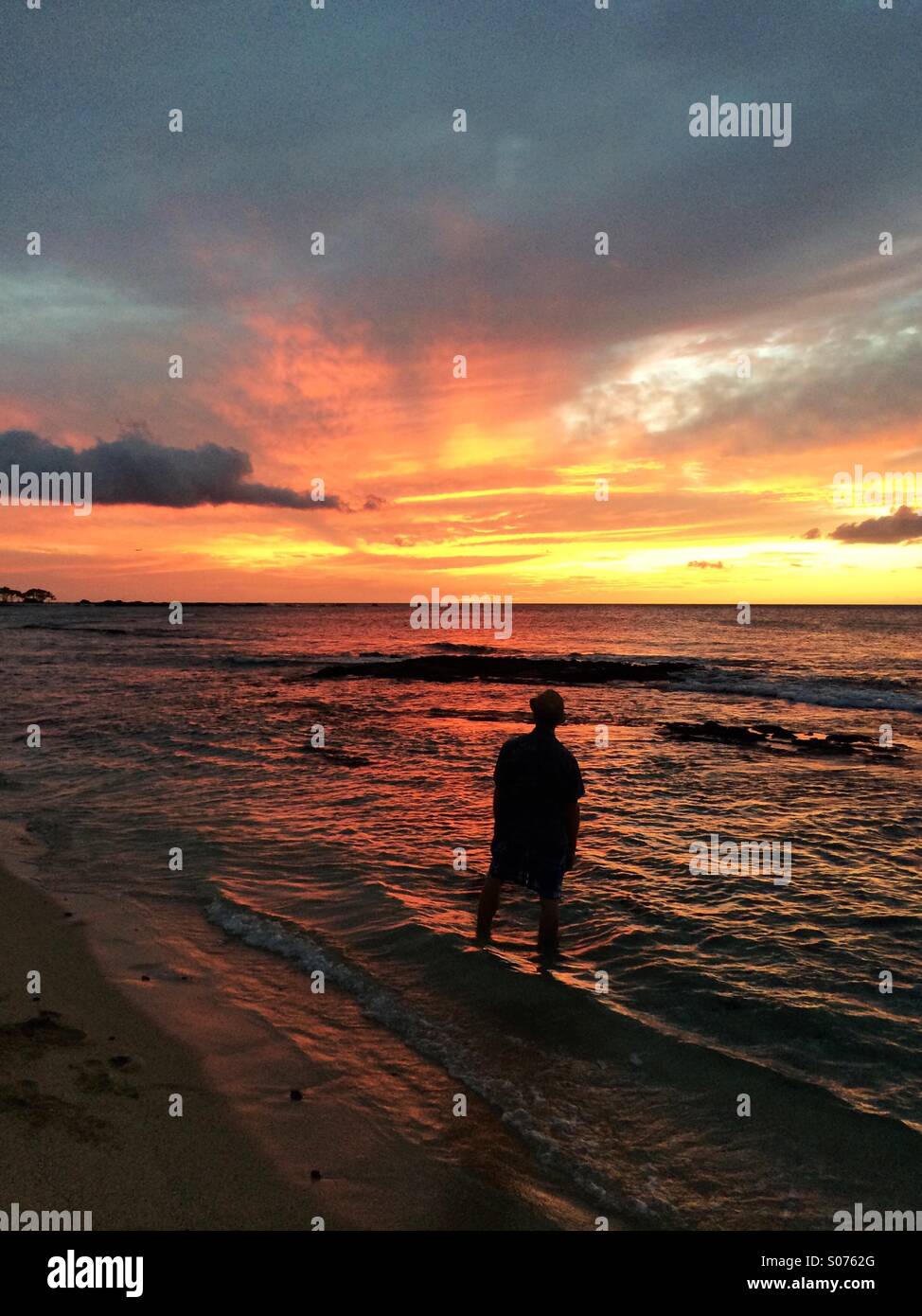 Man watching sunset over ocean in Hawaii - Smartphone Captured Stock Image