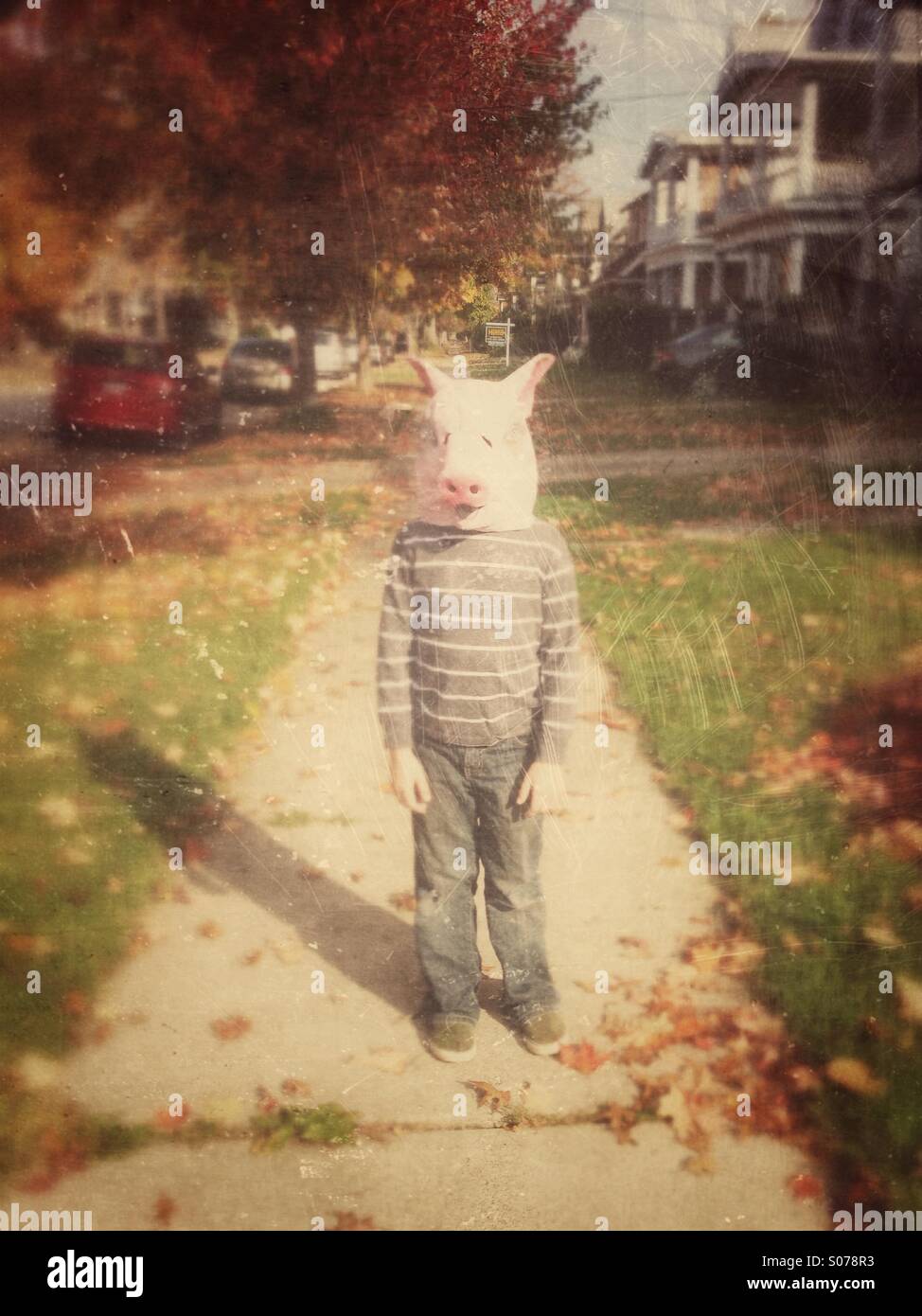 Boy in pig mask on sidewalk Stock Photo