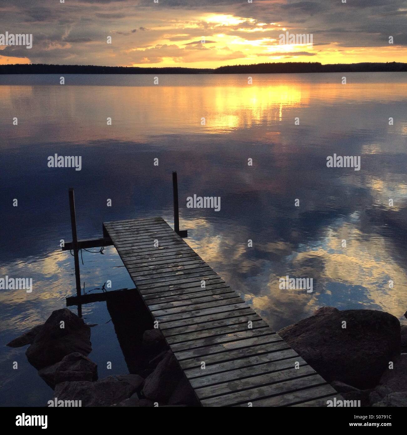 Midnight Arctic sun over a still Finnish lake at a Nordic summerhouse Stock Photo