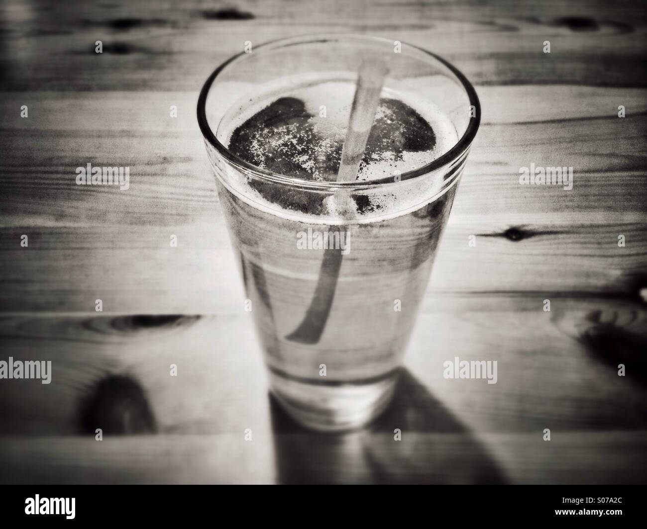 A glass of beer is seen with a straw. Stock Photo