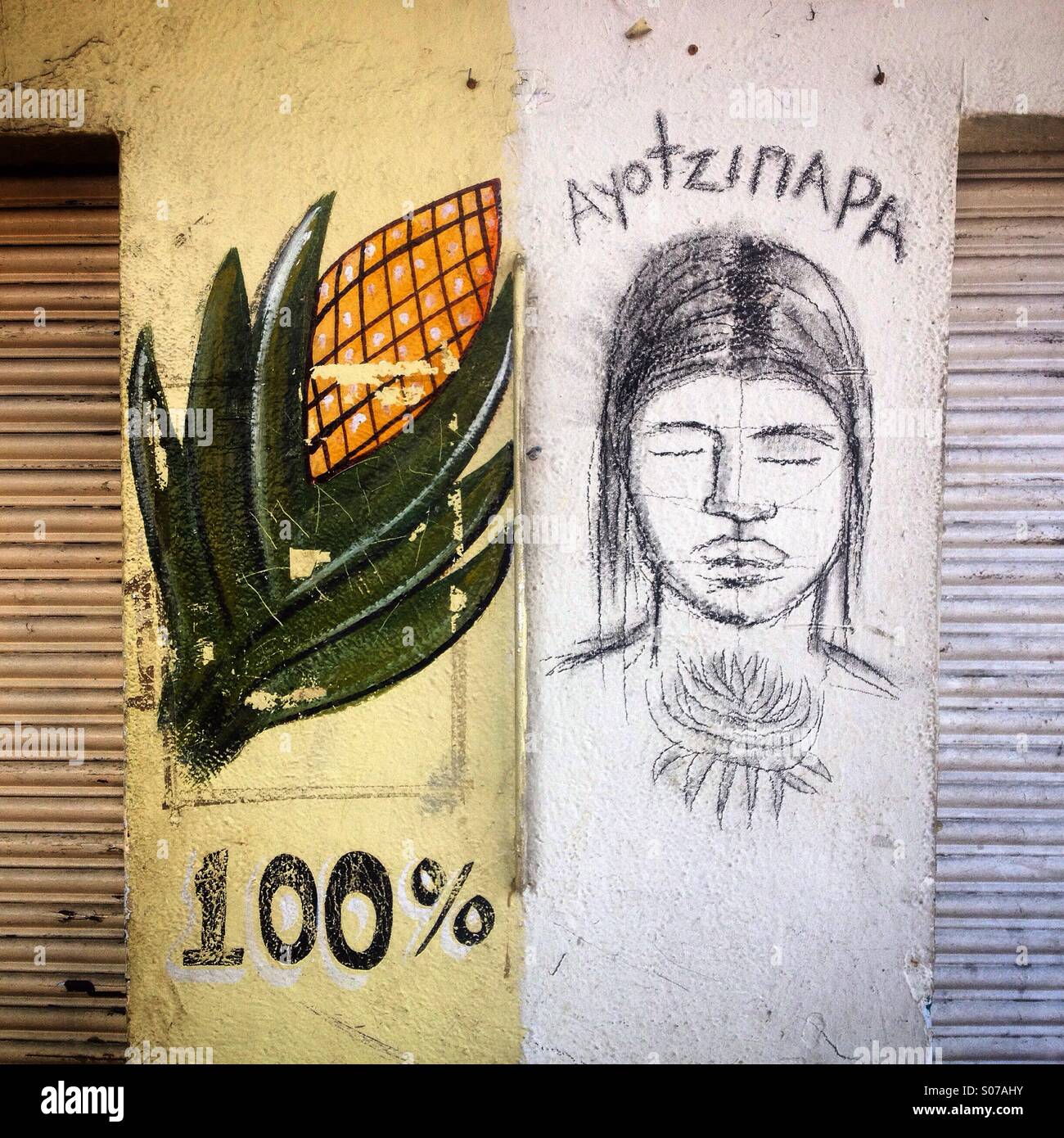 A drawing representing one of 43 missing Mexican students who dissapeared September 26 in Ayotzinapa, covers a wall next to a corn tortillas shop decorated with an ear of corn and a 100% sign painted - Smartphone Captured Stock Image