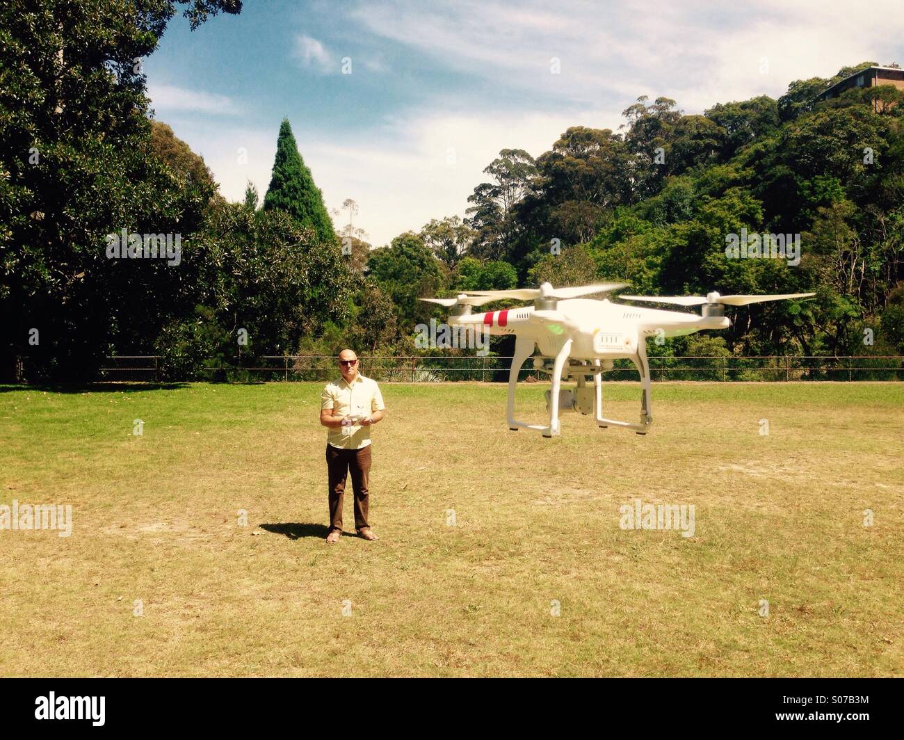 Drone photographer flying his drone in a park Stock Photo - Alamy