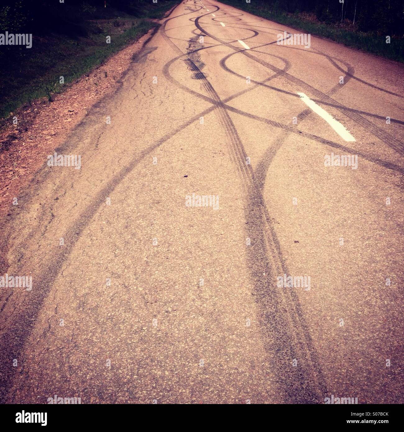 Patterned tyre marks from skidding and burn-off on a traditional Nordic red road Stock Photo