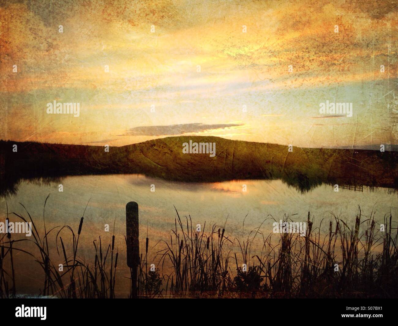 A lake with sunsetting behind a hill. - Smartphone Captured Stock Image