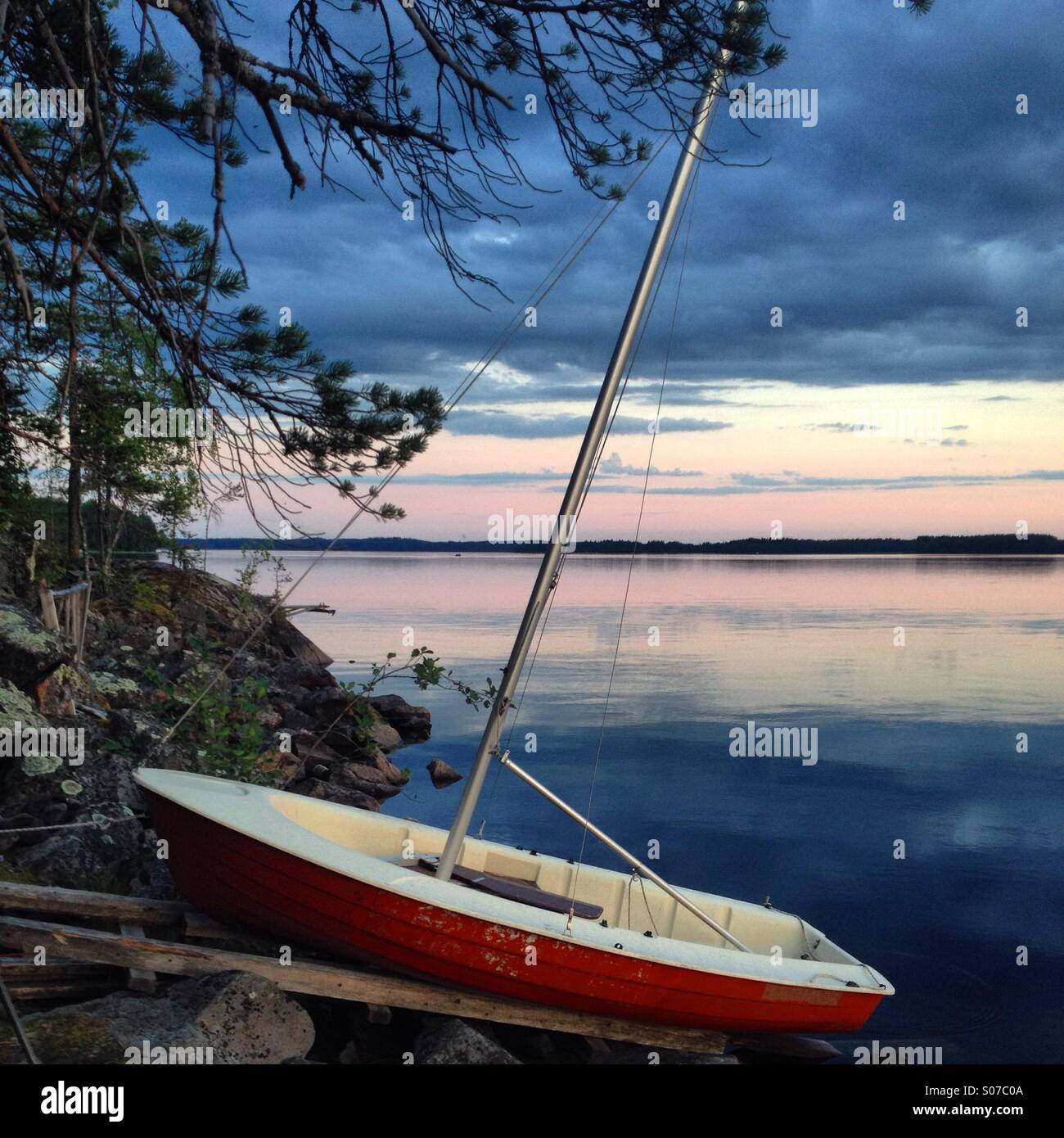 A boat drawn up on a mooring at a North Finland Nordic summerhouse lake in the Arctic Summer midnight sun - Smartphone Captured Stock Image