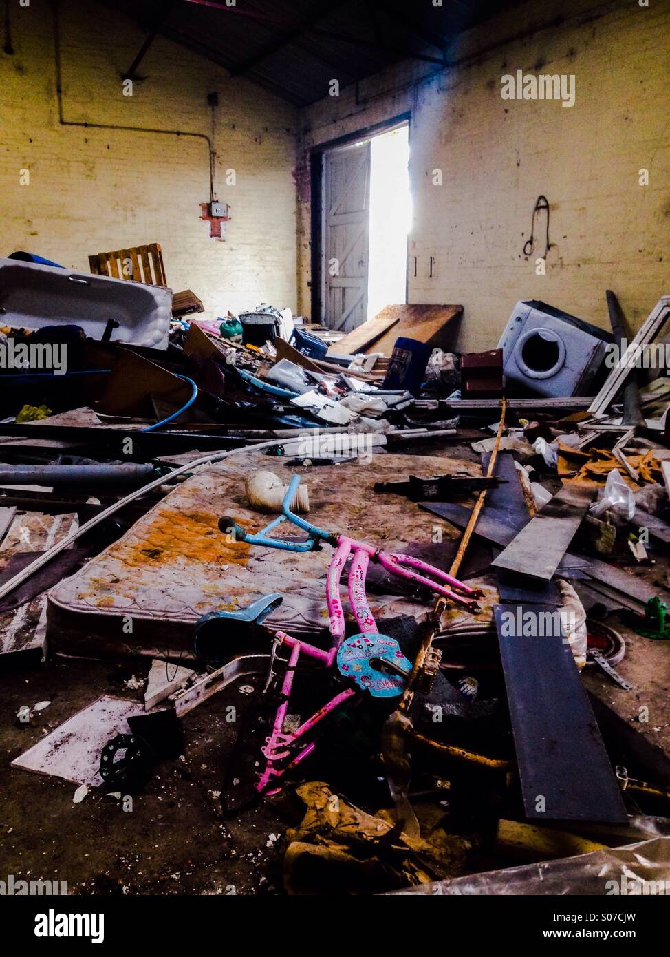 Old abandoned building with childs pink bike in the foreground and washing machine in the background - Smartphone Captured Stock Image