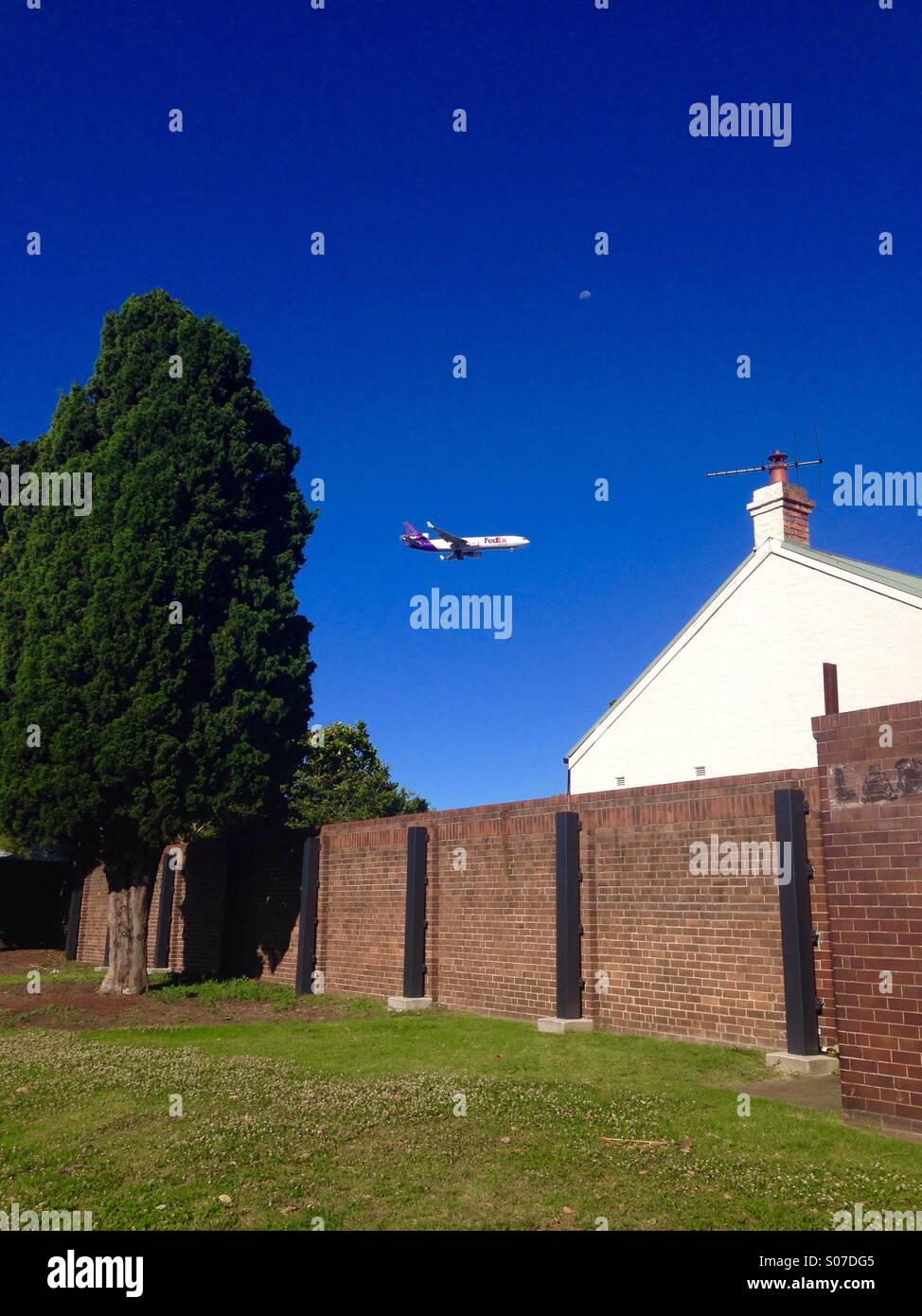 FedEx plane flying over houses, coming in to land - Smartphone Captured Stock Image