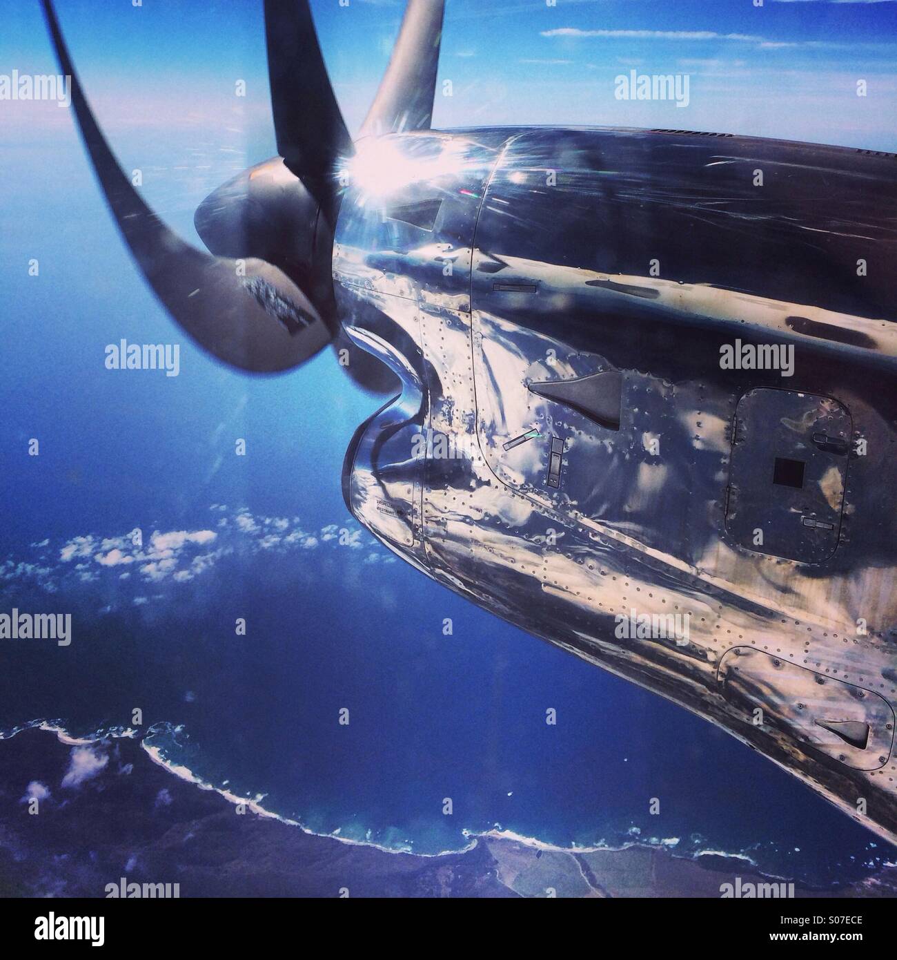 Prop plane over ocean Stock Photo