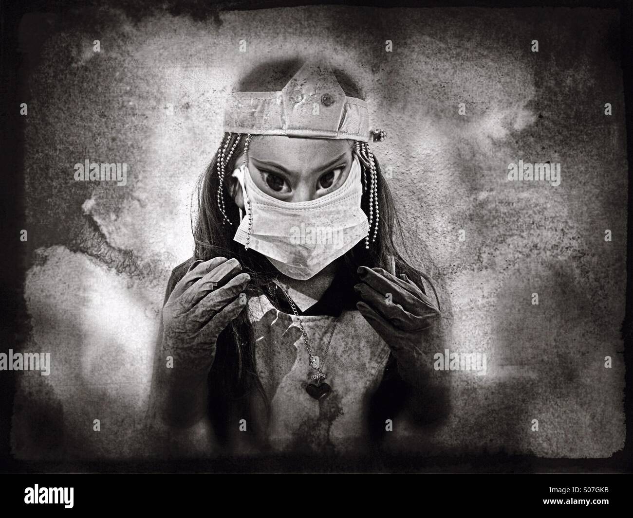 A seven-year-old girl playing dress-up with a surgical mask, gloves and crown with demonic eyes. Stock Photo