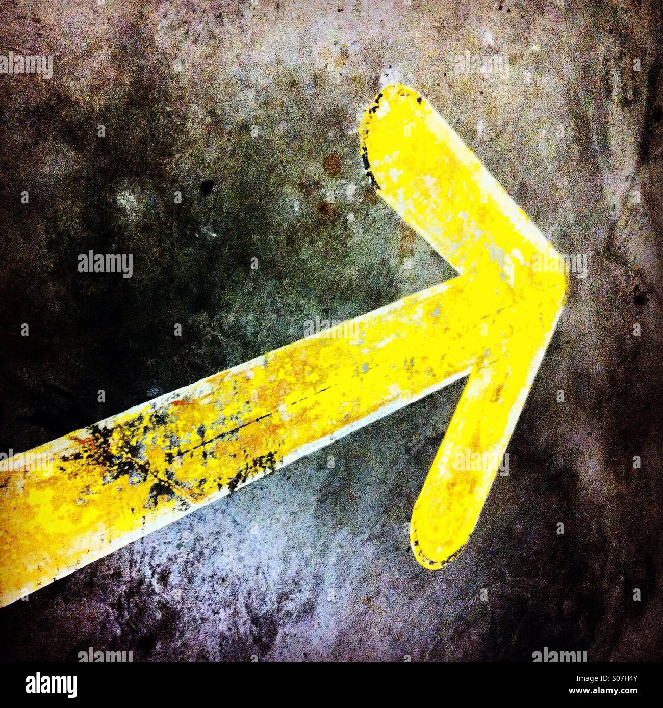 Rough yellow arrow on a wall showing the right direction to go Stock Photo