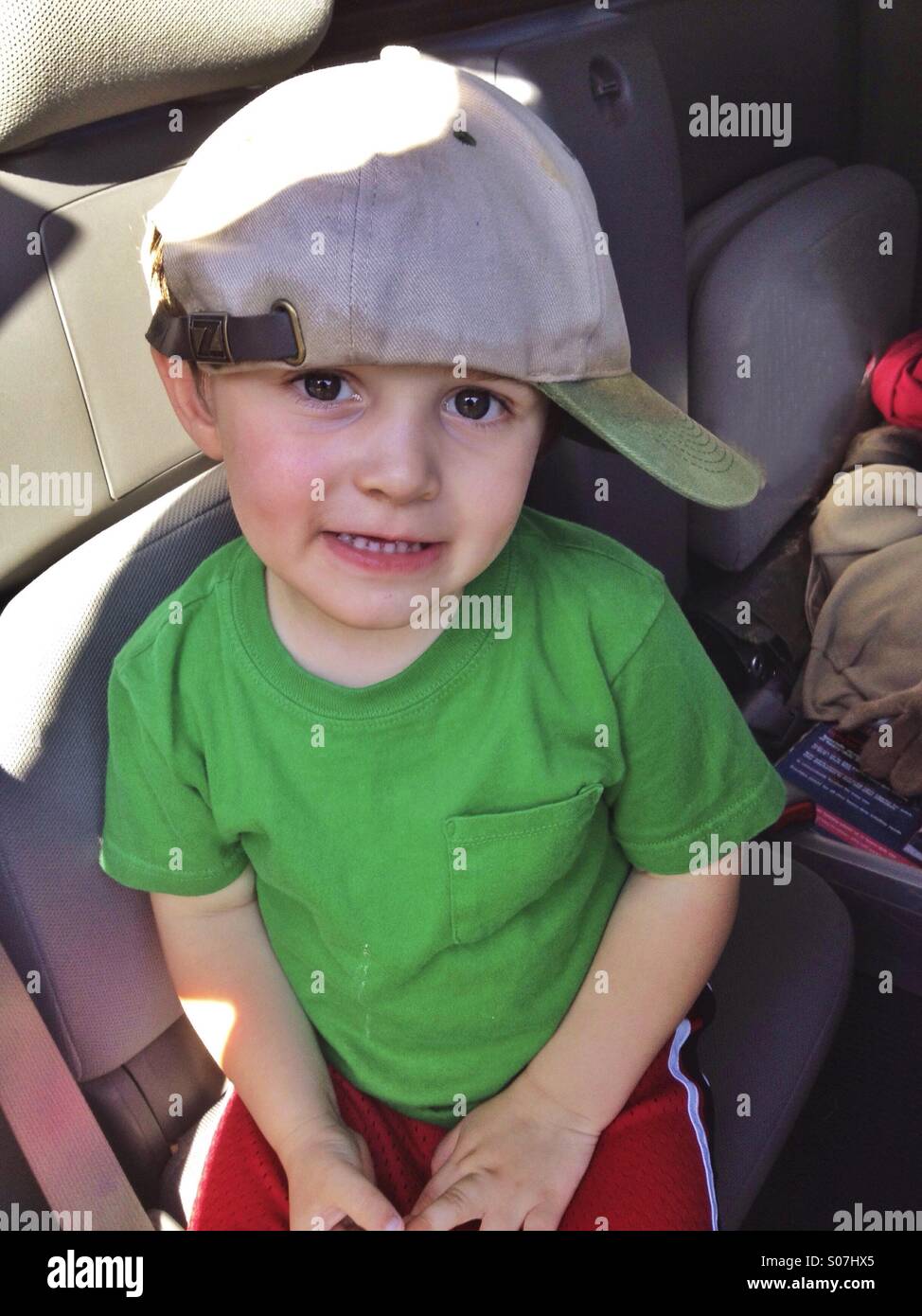 Big man's cap on a little 3 year old boy. Delightful expression Stock