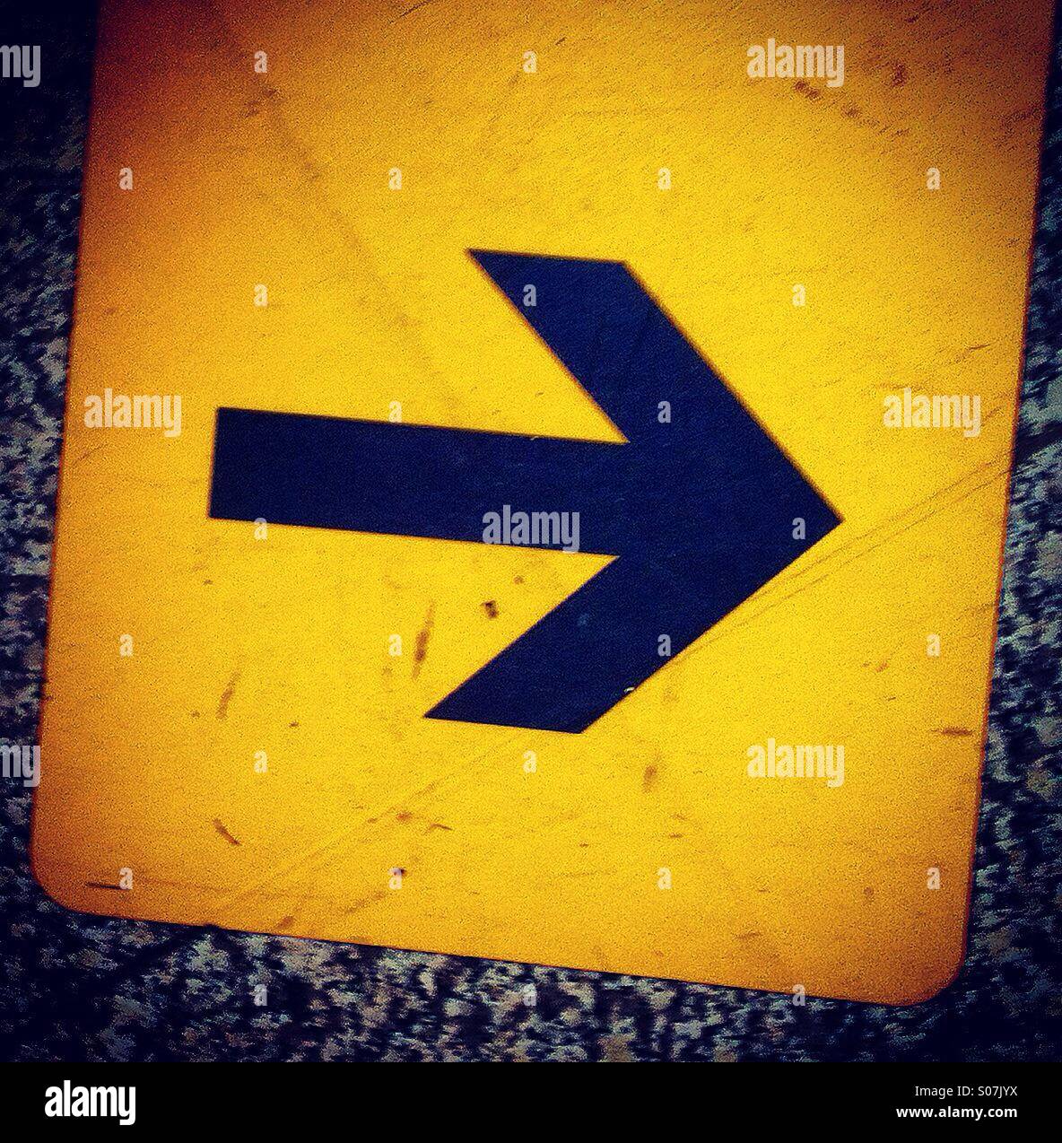 Icon of black arrow on yellow orange sticker - Smartphone Captured Stock Image