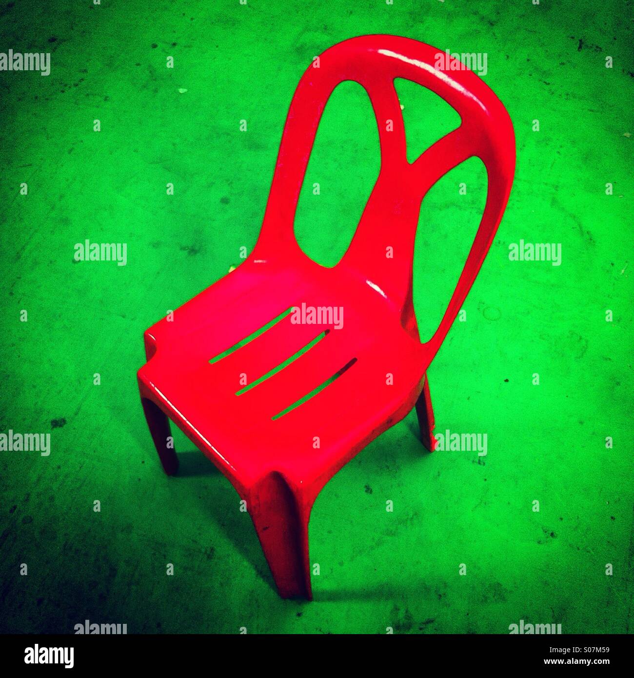 Red plastic chair on green floor - Smartphone Captured Stock Image