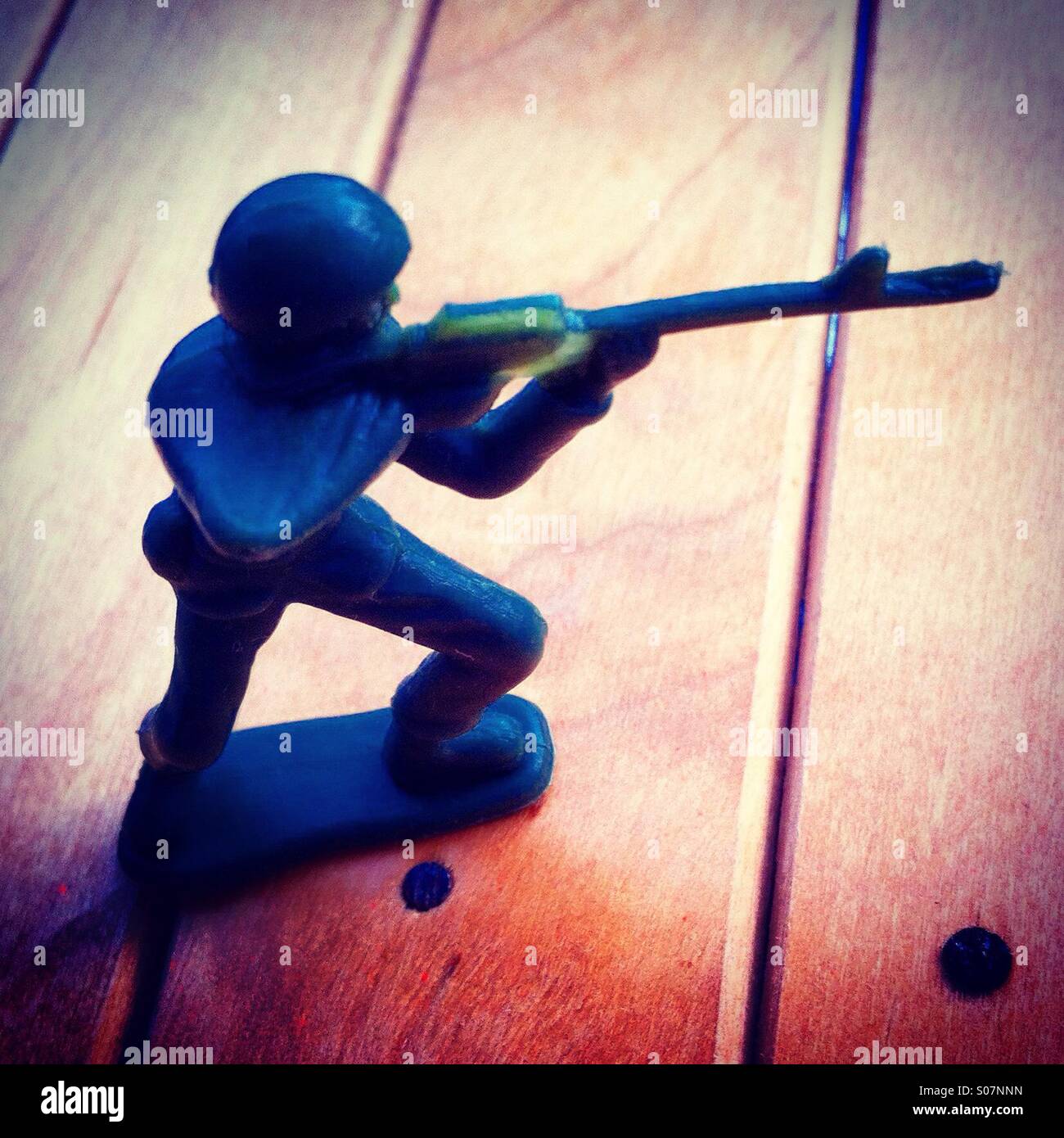 Small plastic soldier figurine shooting with a riffle... Stock Photo