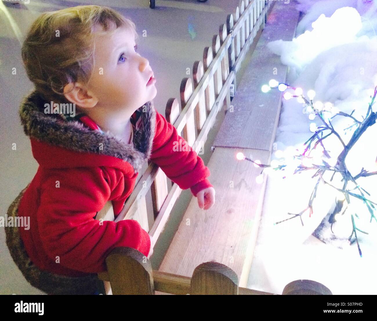 Little girl staring at Christmas lights in wonder Stock Photo