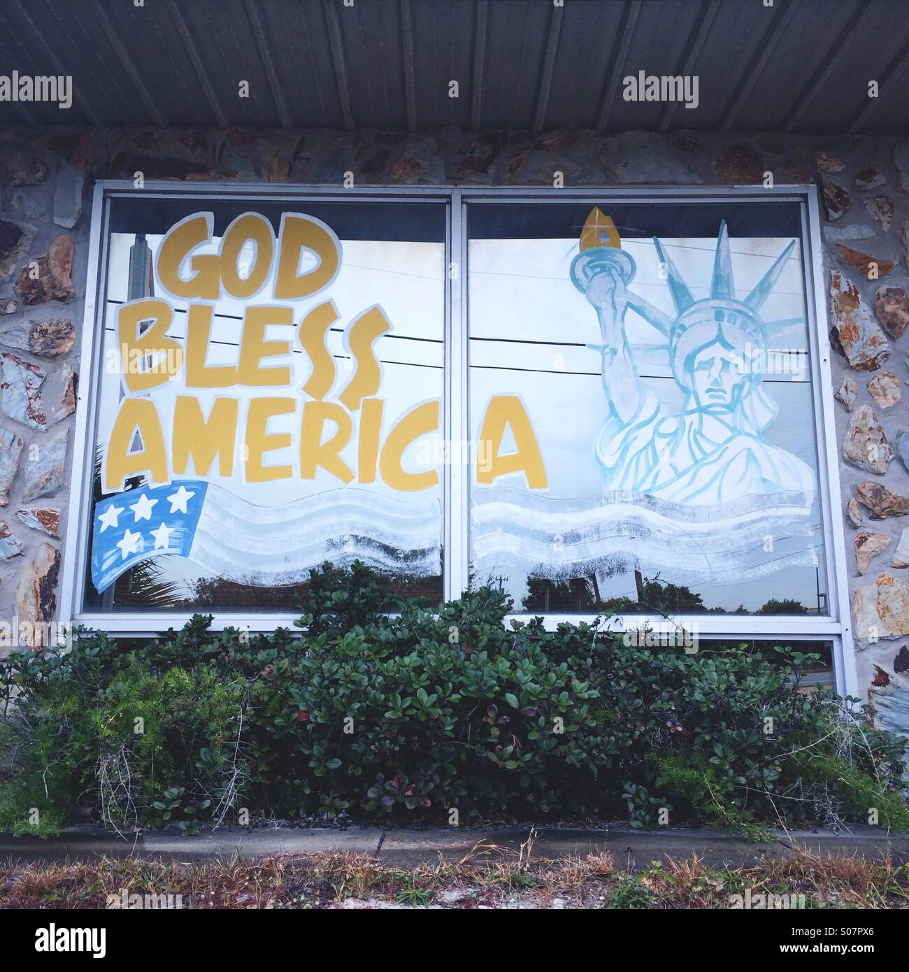 'God Bless America' reads the fading painted sign in a shop window, with an image of the Statue of Liberty. Panama City Beach, Florida, USA. Stock Photo