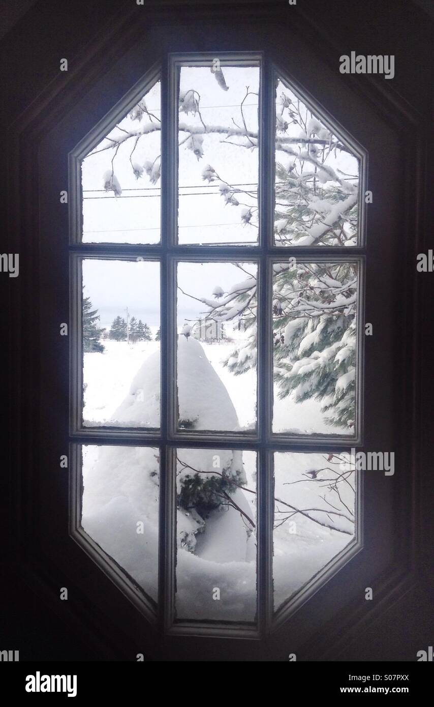 A winter wonderland of a landscape buried in snow as seen through an old fashioned octagon window. - Smartphone Captured Stock Image
