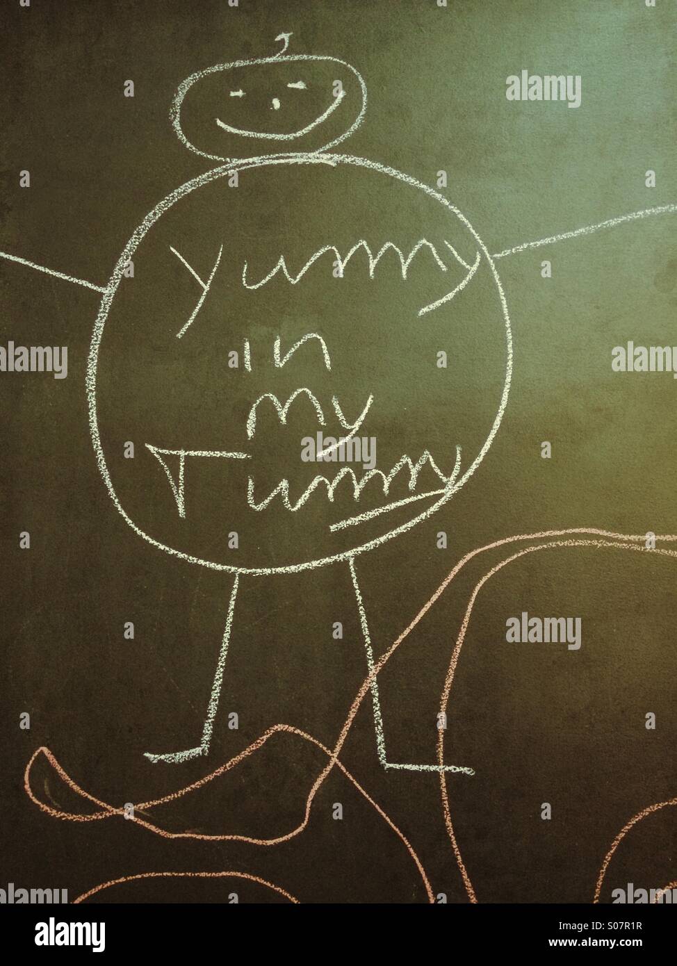 Chalk drawing reads 'yummy in my tummy'. Stock Photo