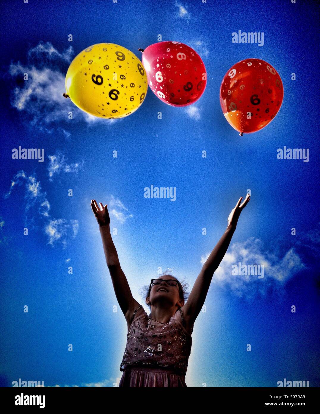 Young girl throwing party balloons in to air Stock Photo