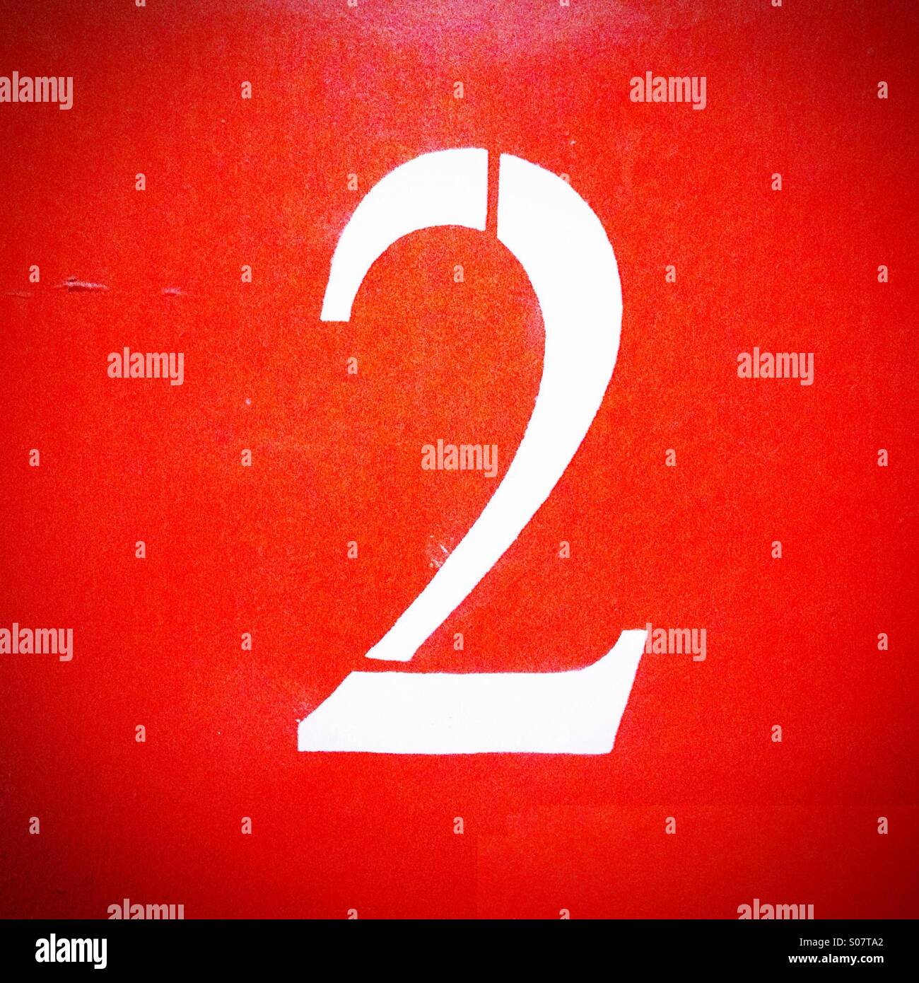 Number 2 painted in white on orange wall - Smartphone Captured Stock Image