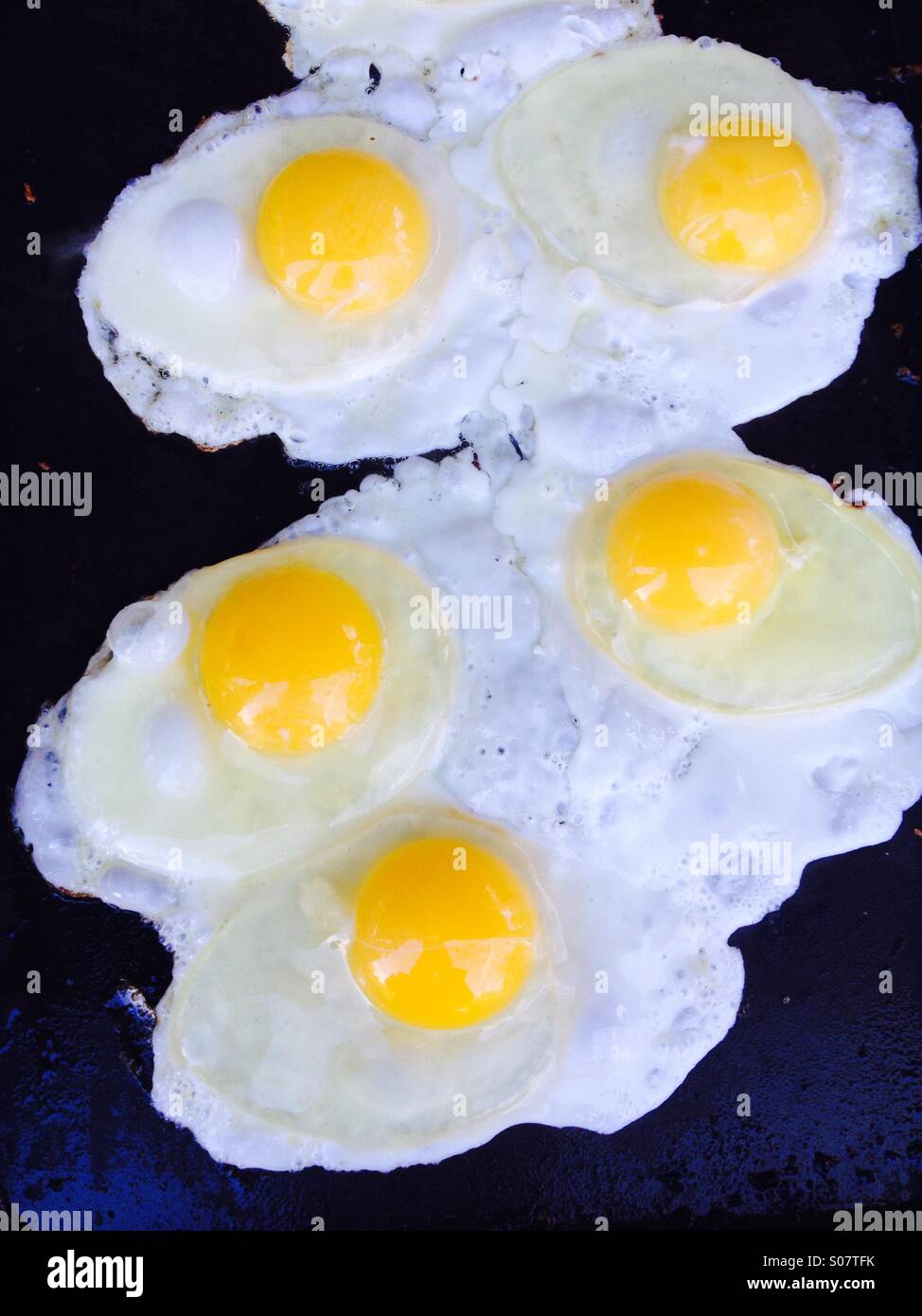 Eggs frying on a griddle Stock Photo Alamy