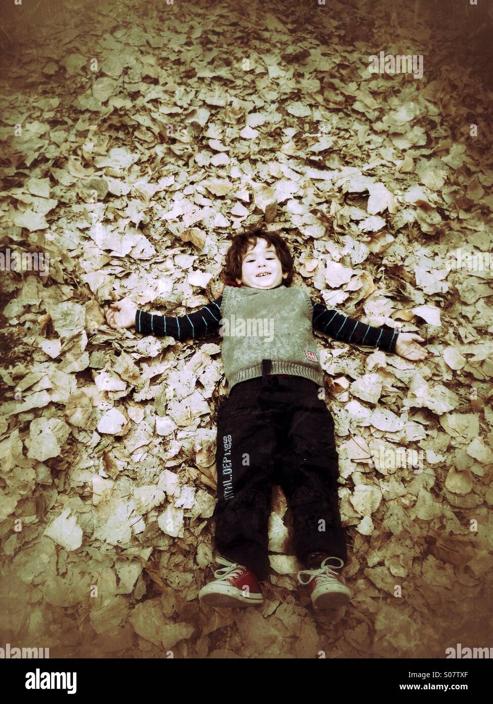 Boy lay down on falling leaves - Smartphone Captured Stock Image