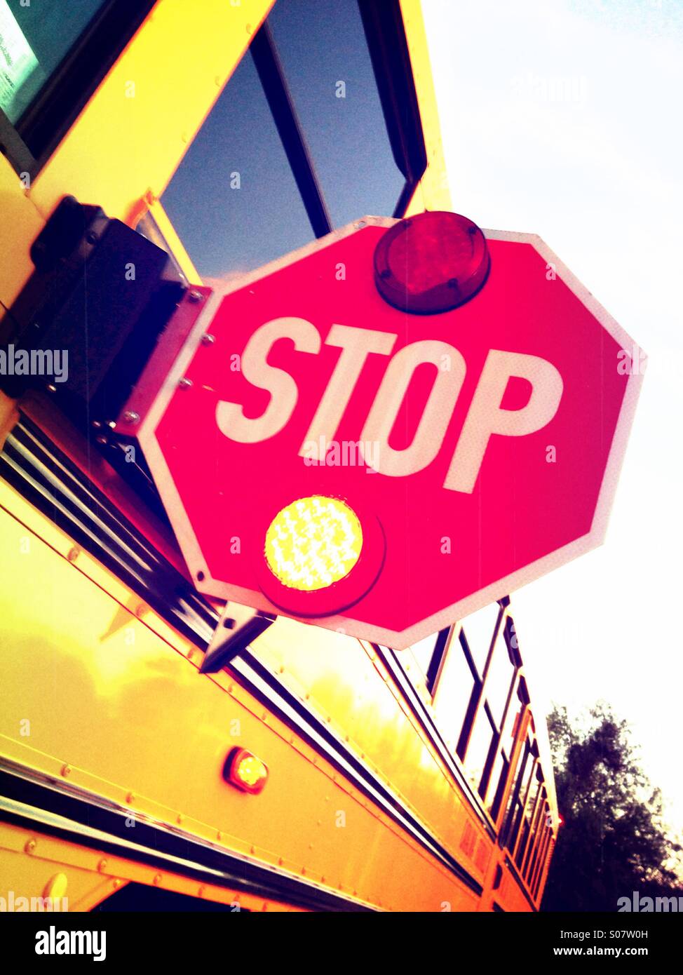 A school bus uses a stop sign and flashing lights to make a stop to pick up children. Stock Photo