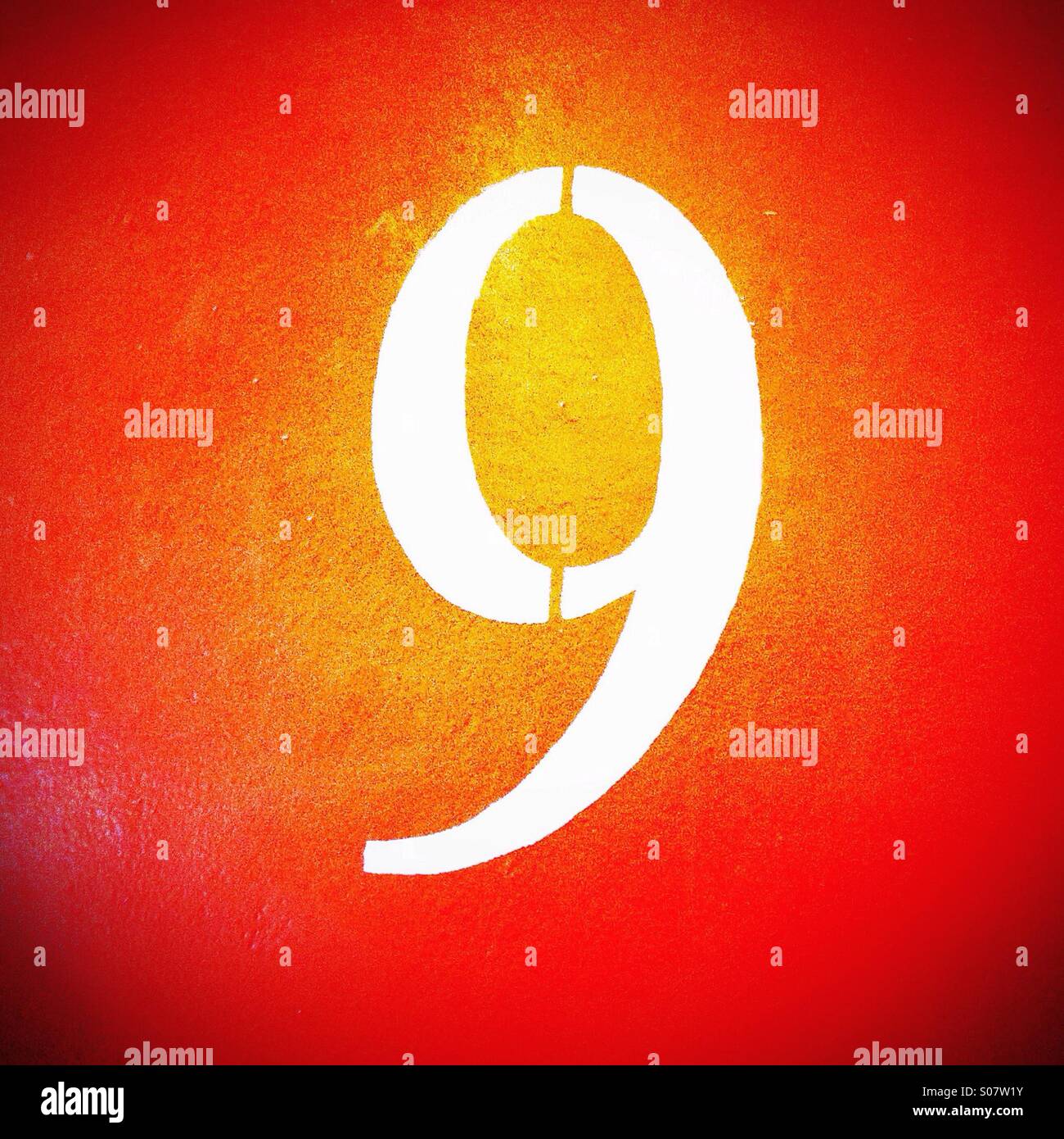 Number 9 in stencil style painted on orange wall Stock Photo