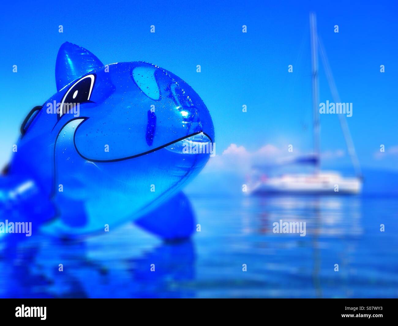 Killer whale attack !                                       Kids inflatable toy with the family's yacht moored behind Stock Photo