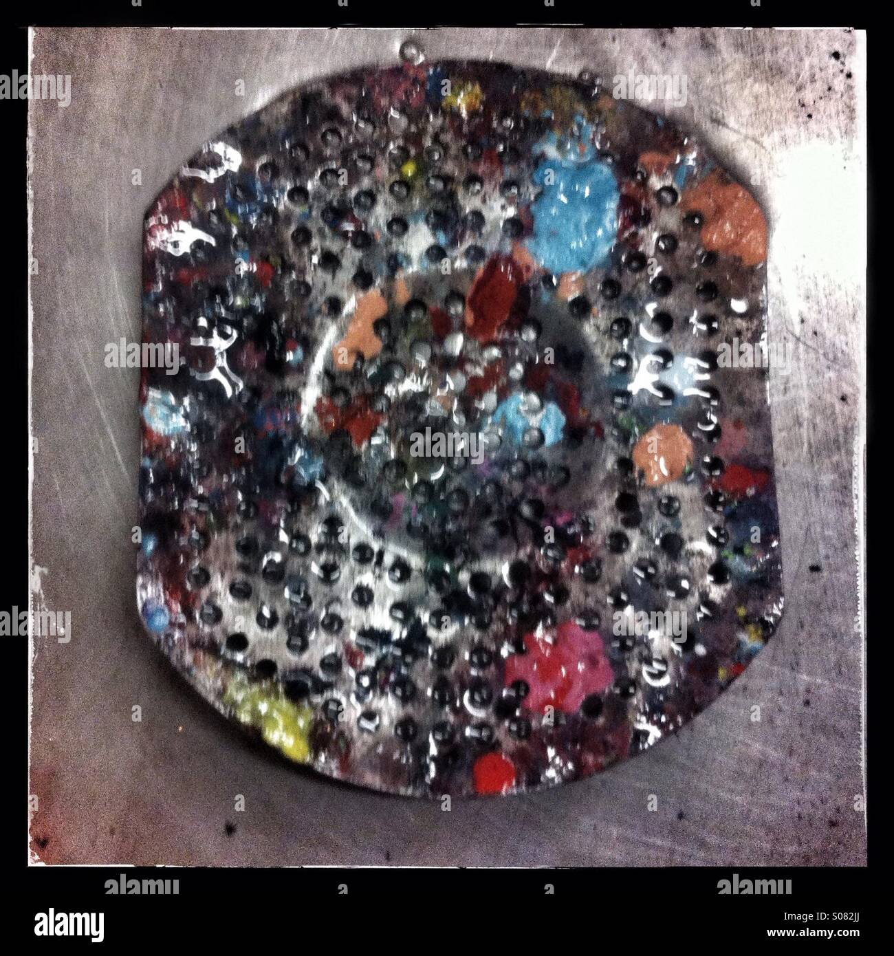 Sink plug strainer covered in coloured paint - Smartphone Captured Stock Image