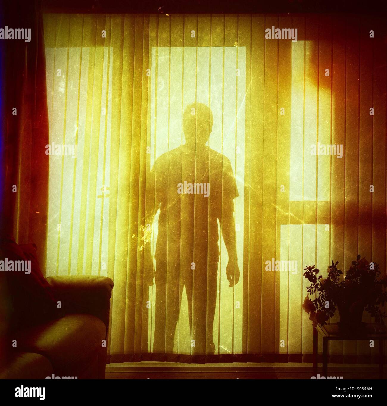 Shadowy threatening figure at a domestic home window - burglar stalker silhouette Stock Photo