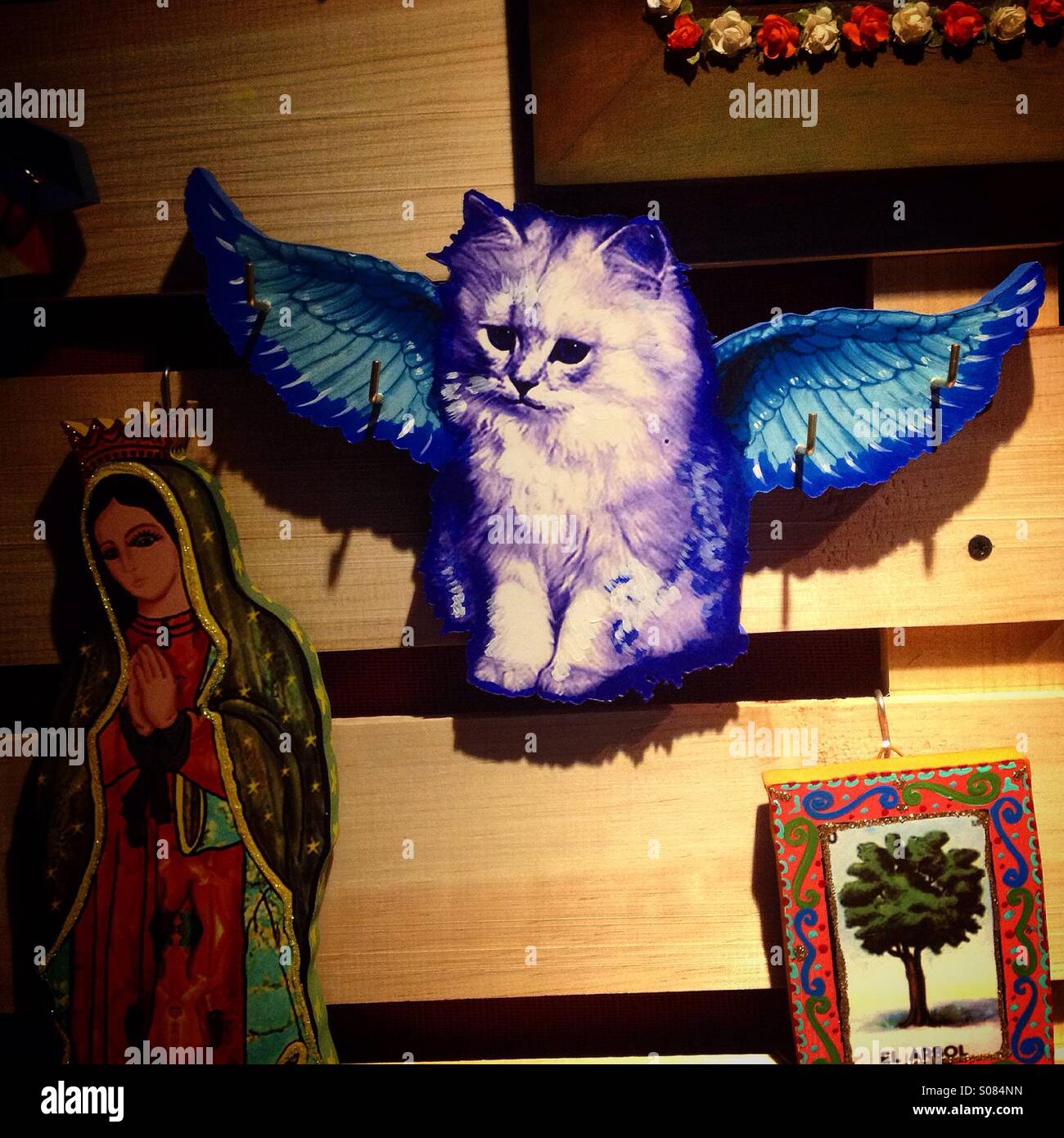 Folk art with an image of a winged white cat flying, an image of Our Lady of Guadalupe and the tree Tarot cart decorates La Luna de Romelia crafts workshop in Mexico City Stock Photo