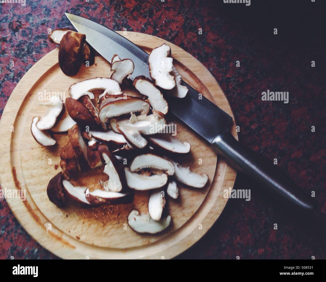 Sliced shiitake mushrooms on a round chopping board Stock Photo