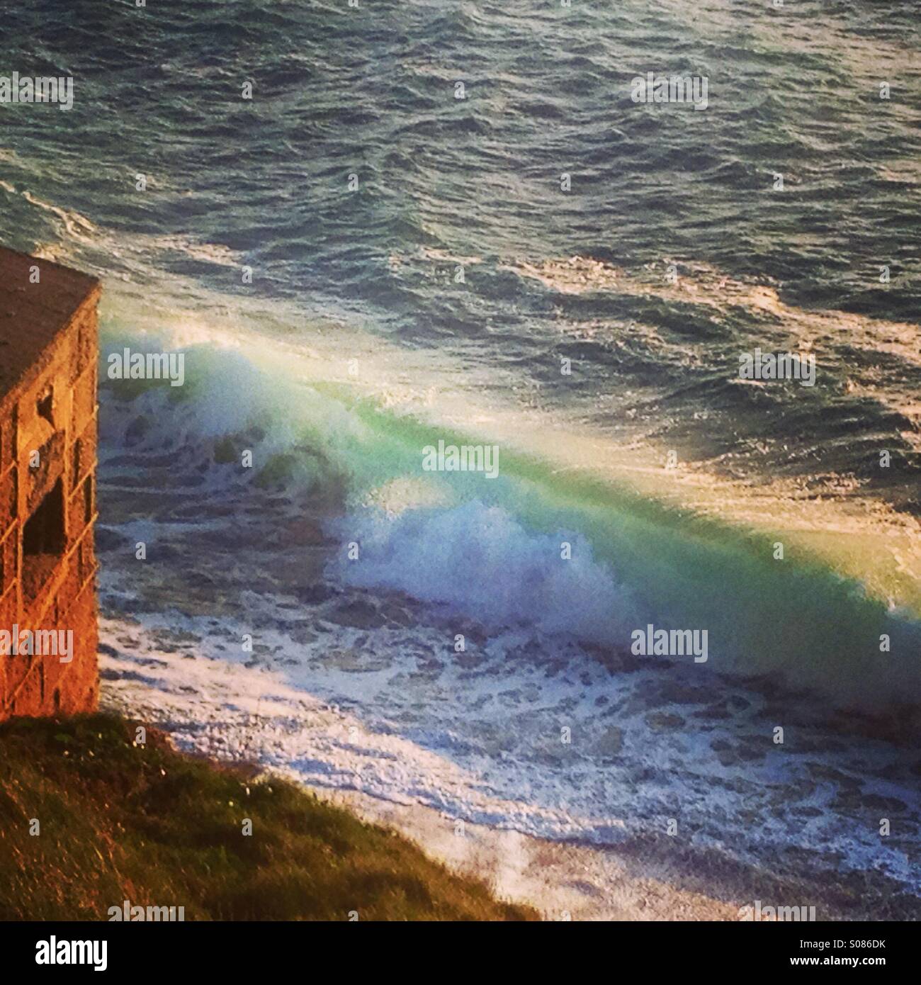 Backlit wave and coastal defences at Porthleven Cornwall - Smartphone Captured Stock Image