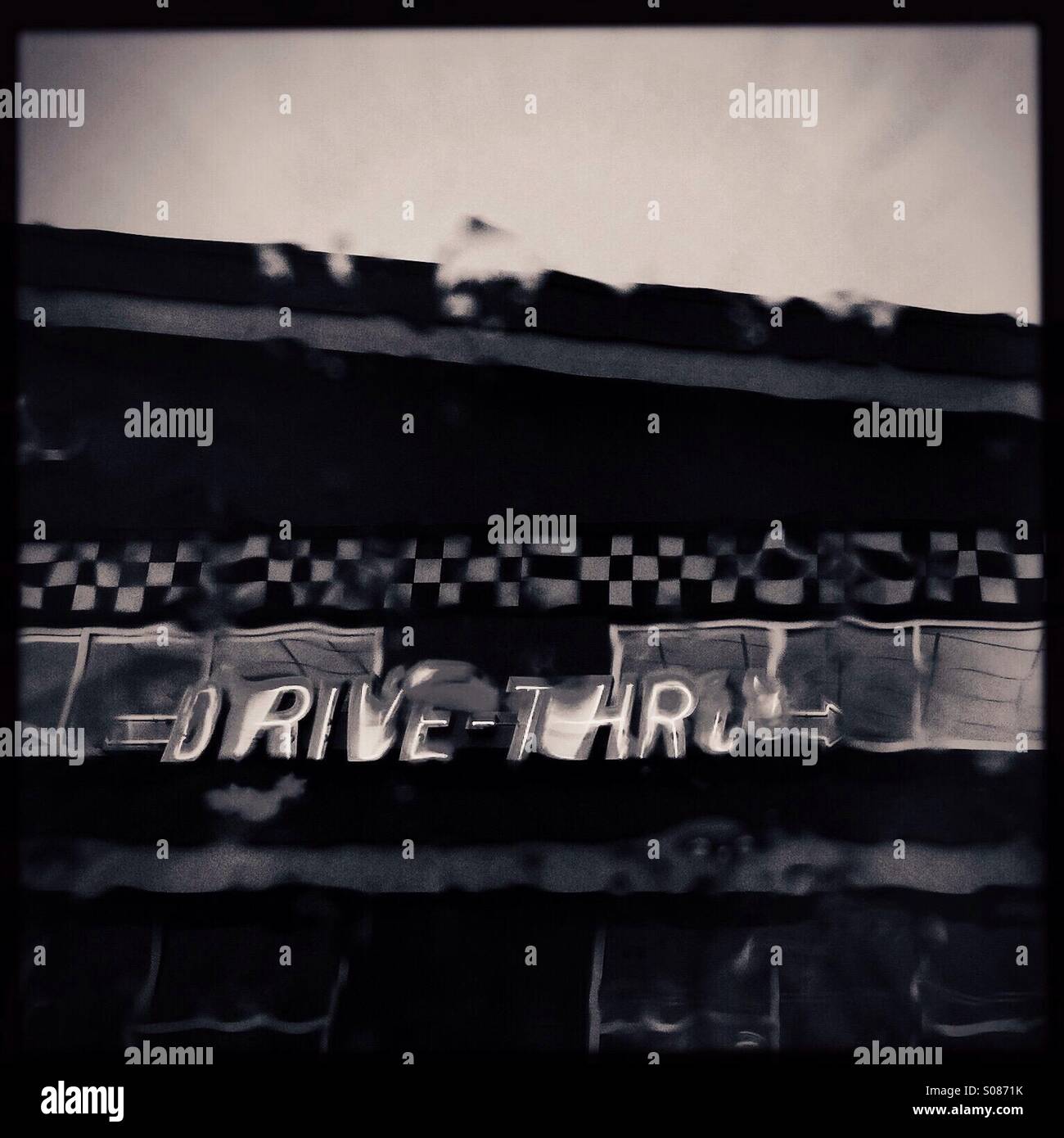 Neon sign for a fast food restaurant drive thru as seen through raindrops on a car windshield. - Smartphone Captured Stock Image